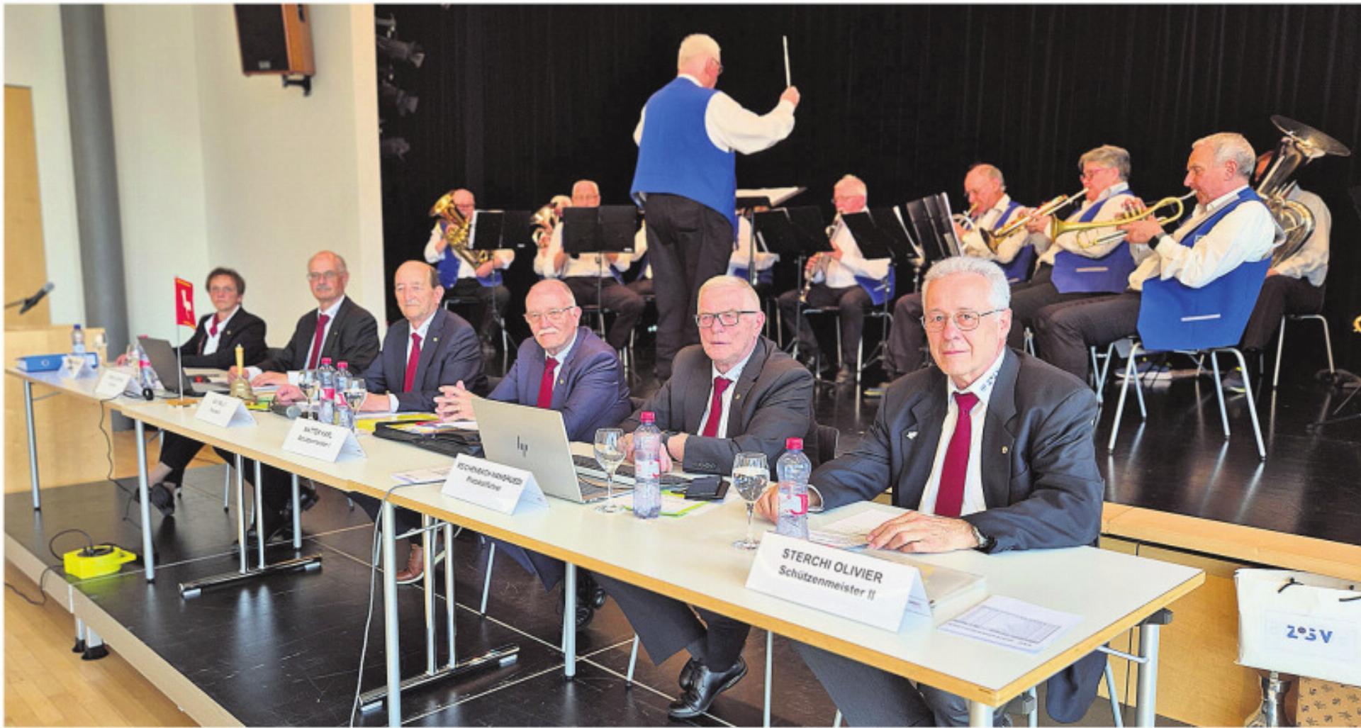 Der Vorstand des Verbandes der Zuger Schützenveteranen: Barbara Grüter, Adrian Eberle, Präsident Willy Näf, Karl Matter, Hansruedi Reichenbach, Olivier Sterchi (von links). Im Hintergrund dirigiert Peter Iten soeben die «Schützenliesel» Foto: zVg - Das Bild wird blockiert. – Möglicherweise durch einen aktiven Adblocker.