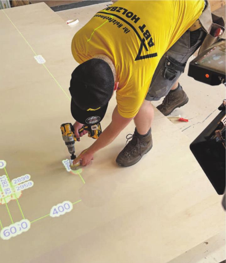 Die 3D-Pläne werden mithilfe von zwei Projektoren auf den Elementtisch projiziert. Dort können die Bauteile präzise ausgelegt und zusammengebaut werden. Die manuelle Erstellung von 2D-Plänen entfällt. Foto: zVg Die 3D-Pläne werden mithilfe von zwei Projektoren auf den Elementtisch projiziert. Dort können die Bauteile präzise ausgelegt und zusammengebaut werden. Die manuelle Erstellung von 2D-Plänen entfällt. Foto: zVg