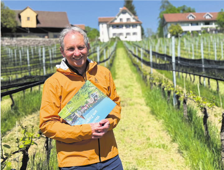 Der Baarer Fotograf Andreas Busslinger unterhalb eines Rebberges im Gebiet Deinikon. In der Hand hält er sein neues Buch «Weinkultur am Zugersee».  Foto: mam